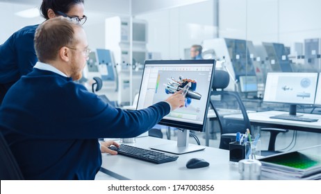 Modern Factory: Female Project Supervisor Talks To A Male Industrial Engineer Who Works On Personal Computer. They Use CAD Software For Design And Development Of Hybrid Hydrogen Engine Prototype