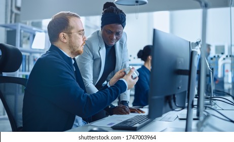 Modern Factory: Female Project Supervisor Talks To A Male Industrial Engineer Who Works On Computer. They Use CAD Software To Design Industrial Machinery In 3D. Working High-Tech Industrial Facility