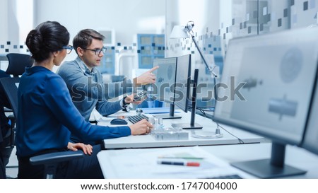 Modern Factory: Male Industrial Engineer Explains to Female Project Supervisor Functions of the Machine Part Comparing it to one on Computer Screen. They use CAD Software for Design, Development