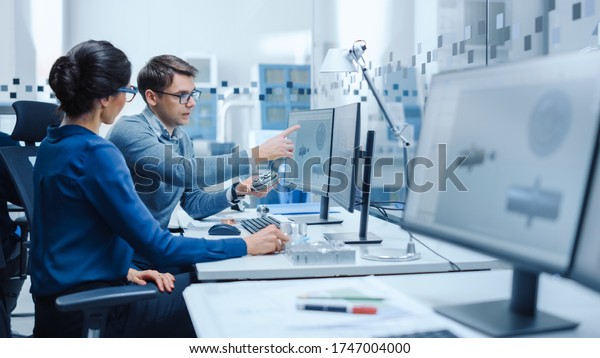 Modern Factory: Male Industrial Engineer\
Explains to Female Project Supervisor Functions of the Machine Part\
Comparing it to one on Computer Screen. They use CAD Software for\
Design, Development