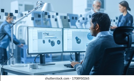 Modern Factory Office: Automotive Engineer Working On PC With Screen Showing 3D Car Concept Made In CAD. Workshop: Workers Use High-Tech Industrial CNC Machinery, Program Robot Arm, Have Meeting