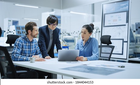 Modern Factory Office Meeting: Female Project Manager, Asian Branch Supervisor Talk With Chief Product Engineer Who Shows Them Laptop Screen. Team Of Professionals Solving Technological Problems