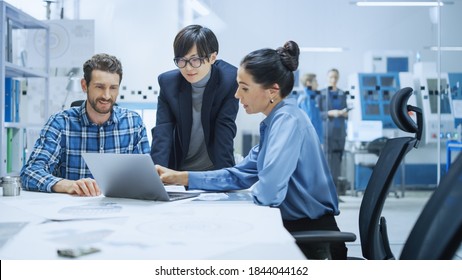 Modern Factory Office Meeting: Female Project Manager, Asian Branch Supervisor Talk With Chief Product Engineer Who Shows Them Laptop Screen. Team Of Professionals Solving Technological Problems