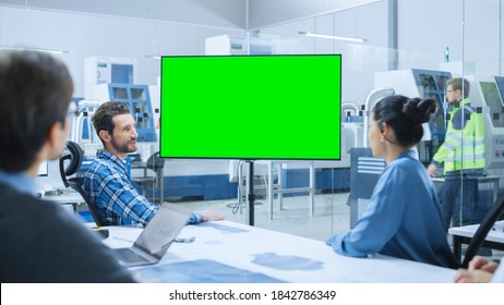 Modern Factory Office Meeting Room: Diverse Team Of Engineers, Managers And Investors Talking At Conference Table, Watching Interactive TV That Shows Green Screen Chroma Key Mock-up