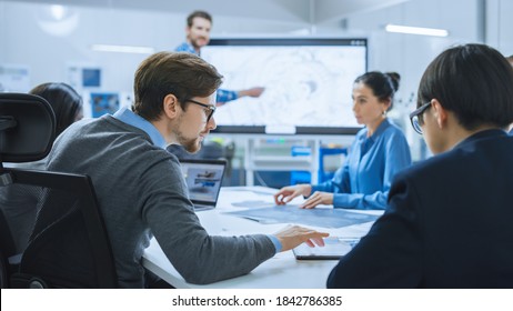 Modern Factory Office Meeting Room: Busy Diverse Team Of Engineers, Managers And Investors Talking At Conference Table, Use Interactive TV, Analyze, Find Solutions, Discuss Concepts.