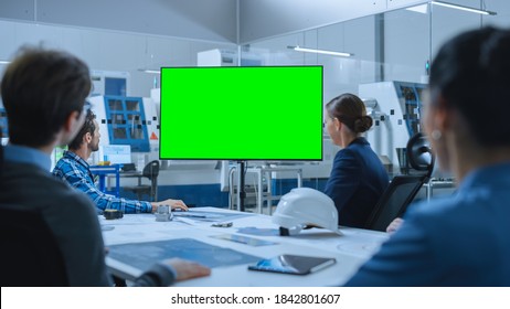 Modern Factory Office Meeting Room: Diverse Team Of Engineers, Managers And Investors Talking At Conference Table, Watching Interactive TV That Shows Green Screen Chroma Key Mock-up