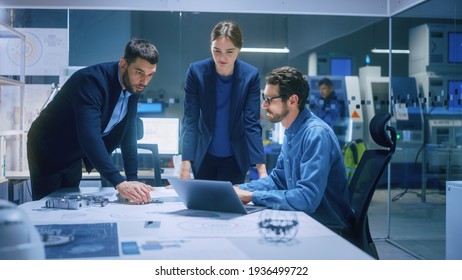Modern Factory Office Meeting Room: Diverse Team of Engineers, Managers Talking at Conference Table, Look at Blueprints, Inspect Mechanism, Use Laptop. High-Tech Facility with CNC Machines - Shutterstock ID 1936499722