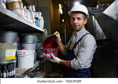 Modern Factory Worker Holding Container With Red Paint In Storehouse