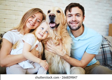 Modern Family With Dog Looking At Camera During Home Rest