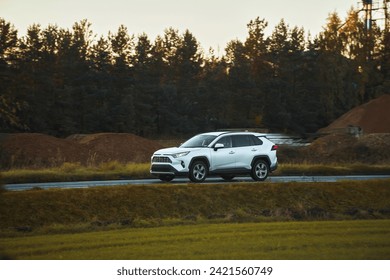 A modern family SUV car journeys along a scenic road with majestic nature and a golden sunset in the backdrop. Subcompact truck with more offroad capabilities and 4WD AWD 4x4 mode. - Powered by Shutterstock