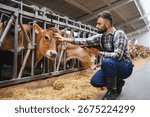 Modern farmer using digital tablet and stroking cow in stable on dairy farm, demonstrating connection between technology and animal care