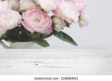 Modern farmhouse style background. White, rustic wooden table background mockup in front of a bunch of pink flowers in a vase. Use for digital product mockup placement or as a background for text. - Powered by Shutterstock