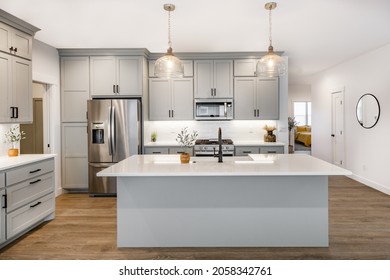 Modern Farmhouse Style Kitchen With Stainless Appliances White Counter Top Raw Wood Dining Table Kitchen Island And Mirror Reflection