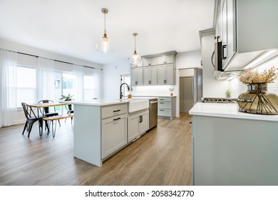 Modern Farmhouse Style Kitchen With Stainless Appliances White Counter Top Raw Wood Dining Table Kitchen Island And Mirror Reflection