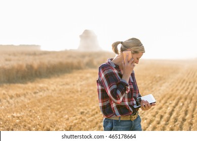 Modern female farmer with tablet on her wheat field