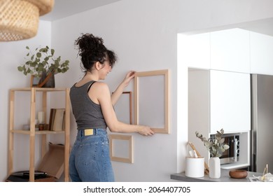 Modern Female Hanging Wall Pictures Photos In Wooden Frame Decorated Scandi Minimalistic Style Room Apartment. Brunette Curly Woman Attaching Elegant Decor Elements Cosiness Home White Light Interior
