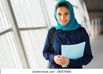 modern female middle eastern college student holding a book
