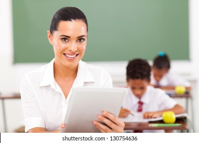 Modern Female School Teacher Using Tablet Computer In Classroom