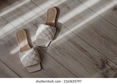 Modern feminine summer sandals, flops of beige color on the floor with natural morning sunlight