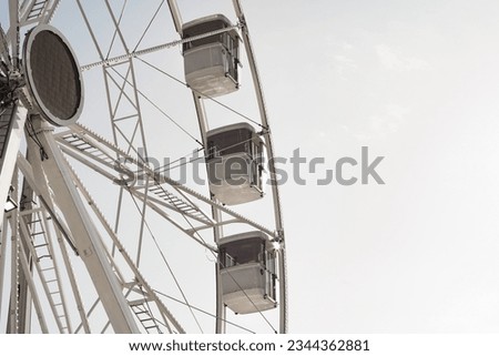 modern ferris wheel with closed cabins at carnival with blue sky no clouds in the background illuminated wide angle close up shot