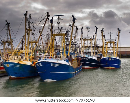 Modern fishing boats under a brooding sky in a dutch fishing harbor
