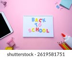 Modern flat lay featuring tablet, colorful pencils and notebook with "Back to School" letters on pink background. Perfect for e-learning, school advertising, remote study promotions, marketing ads.