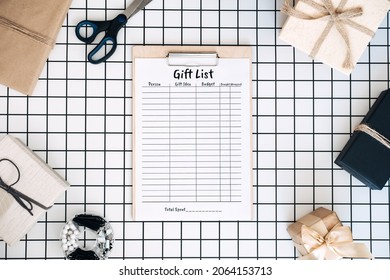 Modern Flat Lay With Holiday Gift List Pintables. Keeping Track Gifts. Clipboard With Paper Gift List, Wrapped Boxes And Wrapping Tools On White Checkered Background
