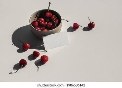 Modern Food Still Life Composition. Ceramic Bowl Of Red Cherries On Beige Table Background In Sunlight. Blank Business Card Mock Ups Scene. Top View. Summer Fruit Composition With Harsh Long Shadows.