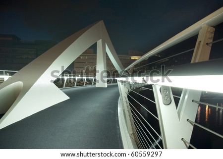 Modern footbridge over River Clyde in Glasgow, Scotland, UK, Europe. Shot from low angle at night to show illuminated handrail and geometric shapes.