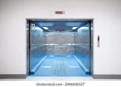 Modern freight elevator featuring a sleek two-section slide-up door design. Empty freight elevator
