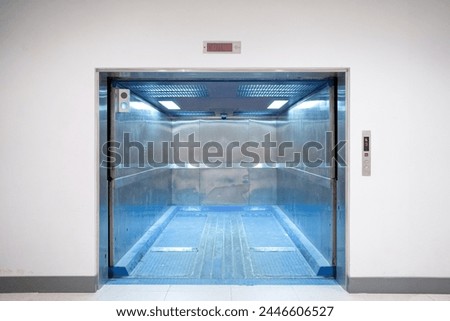 Modern freight elevator featuring a sleek two-section slide-up door design. Empty freight elevator