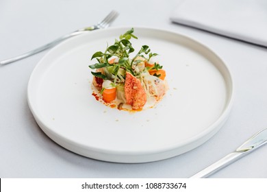 Modern French cuisine: Lobster tail salad including lobster, asparagus and roasted sunflower seeds with white sauce served in white plate.