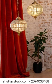 A Modern French Interior With Corduroy Burgundy Curtains And Crystal Chandeliers Against A Brick Wall. Soft Selective Focus.