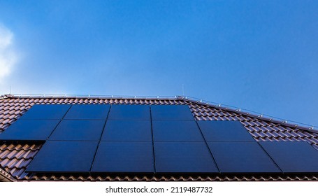 Modern Full Black Solar Panels On The Brown Ceramic Tiles Roof Of A House.