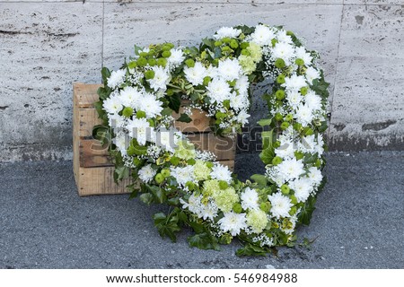 Modern funeral wreath made of white chrysanthemums in flower market Heart shaped funeral wreath in white and green color 