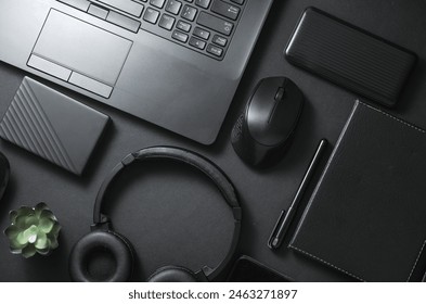 Modern gadgets and accessories in black. Laptop, smartphone, stereo headphones, notepad, external hard drive, power bank on a black background. Working space. Flat lay. Top view - Powered by Shutterstock