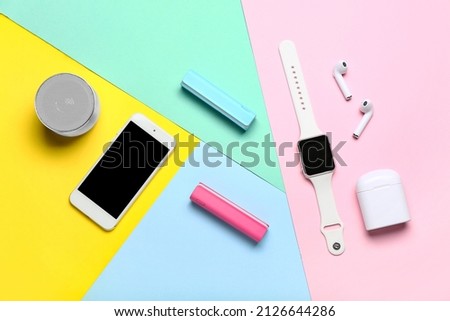 Modern gadgets with power banks on color background