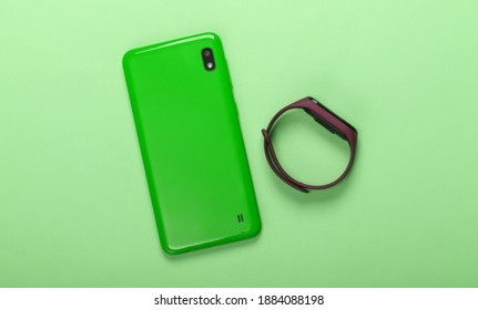 Modern gadgets. Smartphone and smart bracelet on green pastel background. Top view