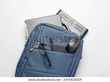 Modern gadgets For work and study. Backpack with laptop, notebook, external hard drive, pc mouse and Graphics tablet on white background. Top view. Flat lay