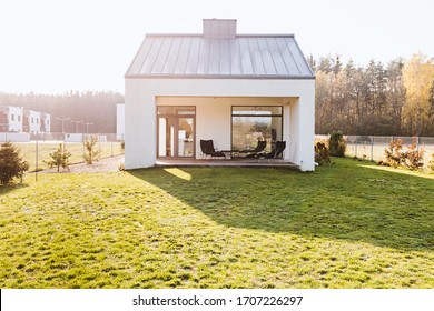 Modern garden furniture on the terrace of stylish suburban house with big green yard