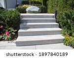 Modern garden and terrace design of a hillside plot with a natural stone stairway decorated with a rock and various flowers and foliage plants