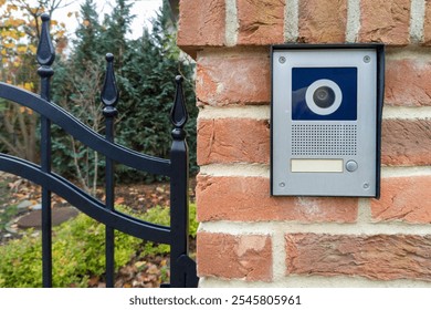 Modern gate intercom with camera on brick wall