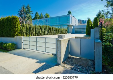 Modern gates with driveway to the luxury house with double doors garage. North America.