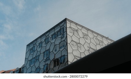 Modern geometric facade with hexagonal pattern windows on contemporary building exterior, architectural detail shot against blue sky