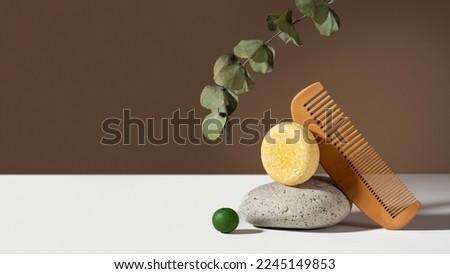 Modern geometric still life composition of a solid shampoo bar. eucalyptus, stone and wooden comb balancing on a brown background. Concept Plastic free, zero waste, low water ingredients. Copy space.