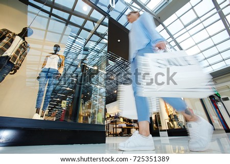 Modern girl looking for trendy clothes on black friday sale while shopping in trade center