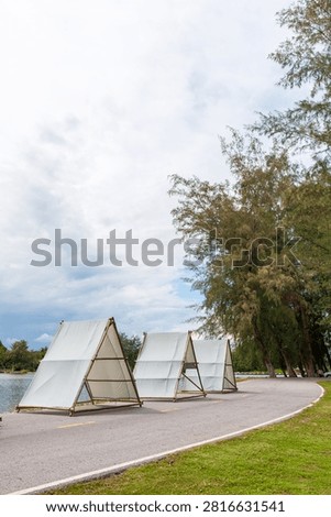 Modern glamping tents surrounded by trees under a dramatic sky. Outdoor travel, eco tourism, camping resort, nature retreat, adventure vacation and sustainable lifestyle concept
