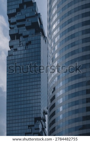 modern glass skyscraper facade with dramatic lookup perspective and geometric lines, contemporary corporate highrise architecture with reflective windows and urban business tower background