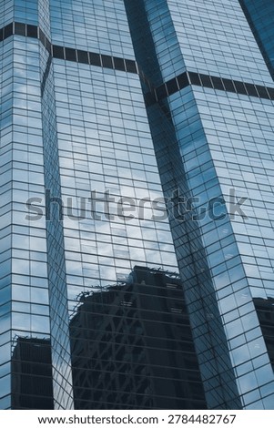 modern glass skyscraper facade with dramatic lookup perspective and geometric lines, contemporary corporate highrise architecture with reflective windows and urban business tower background