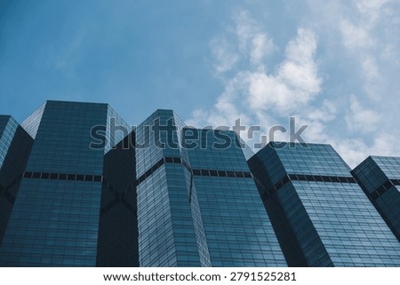 modern glass skyscraper facade with dramatic lookup perspective and geometric lines, contemporary corporate highrise architecture with reflective windows and urban business tower background